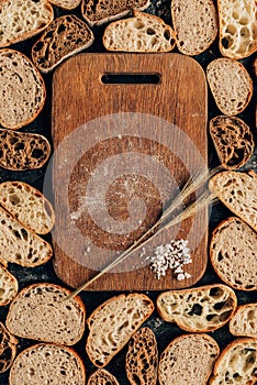 arranged pieces of bread and wooden cutting board with wheat and salt