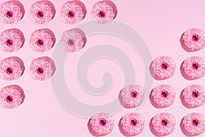 Arranged pink ring donuts like triangle with glaze and white crumbs on a pink pastel background. Pattern. Copy space