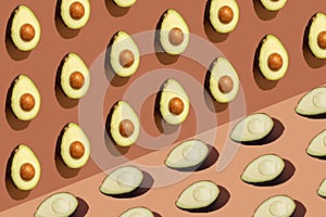 Arranged up and down avocado on a brown background. Minimal pattern.