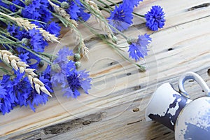 Arrangement of blue cornflowers and wheat ears on wooden background