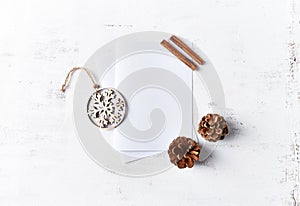 An arrangement of Christmas decorations and blank paper cards on white wooden background. Flatlay. Copy space