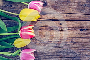 Arrangement of colorful tulips on a rustic wooden table, text space