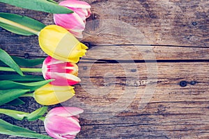 Arrangement of colorful tulips on a rustic wooden table, text space