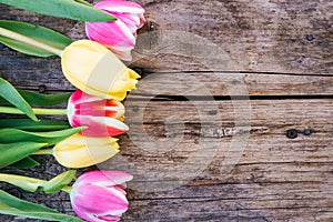 Arrangement of colorful tulips on a rustic wooden table, text space