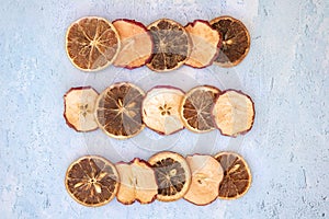 Arrangement of dried apple and dried orange slices on blue background