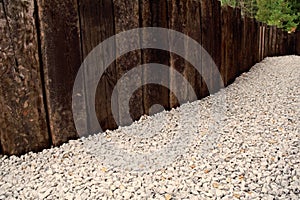 Arrangement of the space around the house in the form of a wooden fence and small white pebbles