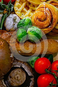 The arrangement of various breads and vegetables is still,cinnamao roll,garlic,Brussels Sprouts, tomato focus on Brussels sprouts