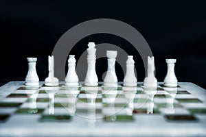 Arrangement of white chess figures without pawns on marble green and white chess desk. Leadership in business is right start