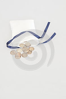 Arras, coins for weddings. Silver and copper coins with religious words in texture coming out of a small cloth sack.