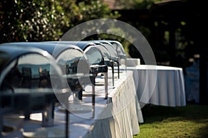 an array of buffet chafing dishes at an outdoor wedding reception