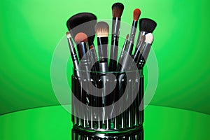 array of professional makeup brushes on neon green backdrop