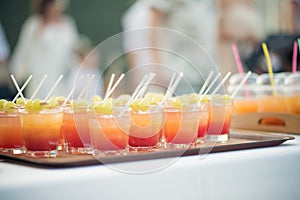 an array of ready made drinks with straws on a tray for a wedding reception