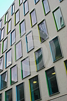 Array of rectangular windows with colorful frames in yellow, green, cyan and blue on gray modern facade of Vicki Sara Building