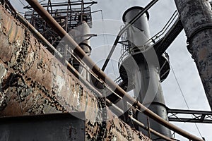 Array of riveted pipes and smokestacks, catwalks and ladders of industrial site