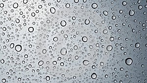 An array of water droplets covers a smooth glass surface creating a