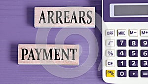 ARREARS PAYMENT - words on wooden blocks with a calculator in the background