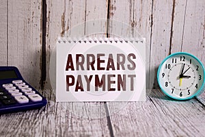 Arrears Payment write on a book isolated on Wooden Table.