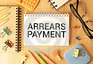 Arrears Payment write on a book isolated on Wooden Table