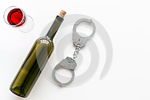 Arrest for drunk driving concept. Handcuffs near wine glass and bottle on white background top view copy space
