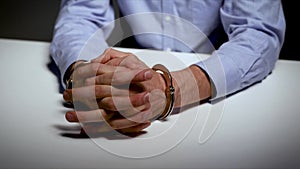 Arrest - hands with handcuffs on the table