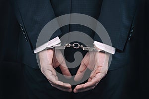 Arrested businessman in handcuffs with hands behind back