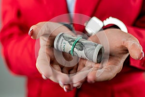 Arrested girl with hands in handcuffs with a huge amount of dollar bills.