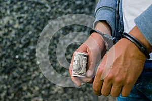 arrested Hispanic man in handcuffs with dollar banknote. Arreste