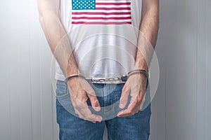 Arrested man with cuffed hands wearing shirt with USA flag