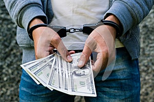 Arrested rowdy in handcuffs counting dollar banknote. Arrested f