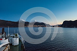 Arriving in Maloy, Norway with cruise ship in early morning with snow capped mountains on clear winter day photo