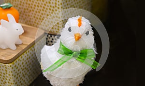 Arrogant looking white decrative easter chick with green bow with baskets and toy bunny in background - room for copy