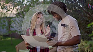 Arrogant self-confident Caucasian woman disagree with African American man discussing project on picnic outdoors