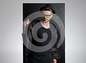 Arrogant smart casual man holding black coat in studio