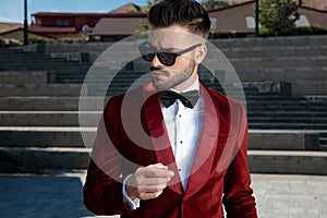 Arrogant young elegant man wearing red velvet tuxedo outdoor