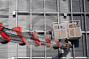 Arrow of a construction truck crane with a cradle on the facade of a building, repair work, background