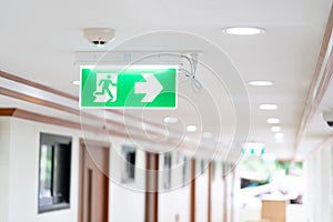 A Arrow light box sign of EMERGENCY FIRE EXIT is hung on the ceiling in hospital walkway, Idea for event fire or evacuation drills