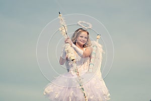 Arrow of love. Portrait of a cupid little girl. Cute teen cupid on the cloud - sky background. Innocent Girl with angel