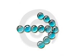 Arrow made of blue transparent glass bead stone pebbles isolated on white background. Close up.