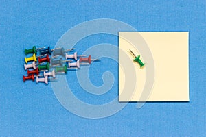 Arrow made from coloured pushpins aiming note paper