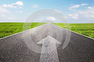 Arrow sign pointing forward on long empty straight road photo