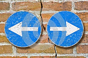 Arrow signs against a brick wall indicating to go left and right - Choice concept, dividing, divorce or separation