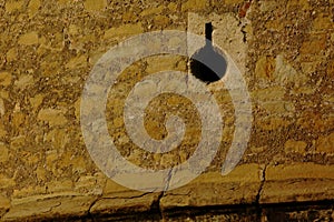 arrow slit. in stone exterior wall. rough stone turret of fortress. elevation detail.