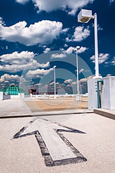 Arrow and street lamp under a partly cloudy sky, on top of a par