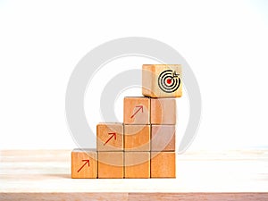 Arrow upward to the target icon symbol on wooden cube blocks, bar graph chart steps on white background, profit planning,