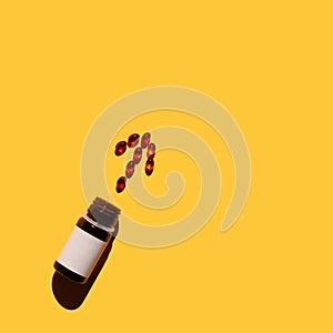 Arrow of vitamins, spilling out of a bottle on yellow background.