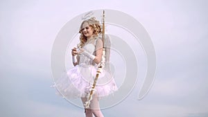 Arrow and wings. Teenager Cupid. Happy teenage angel girl. A child in the clothes of an angel on sky background. Space