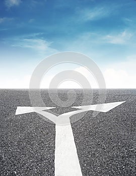 Arrows leading sign on asphalt road and blue sky