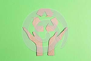 Arrows recycle eco symbol in cardboard hands silhouette on green background