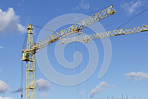 The arrows of the Yellow Tower Cranes intersect against a blue sky.