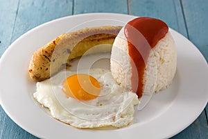 Arroz a la cubana Typical Cuban rice with fried banana and fried egg on a plate on wood photo